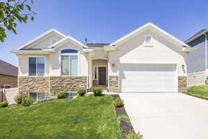 View of front of home featuring stone siding, stucco siding, driveway, and a garage