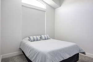 Carpeted bedroom featuring baseboards and vaulted ceiling
