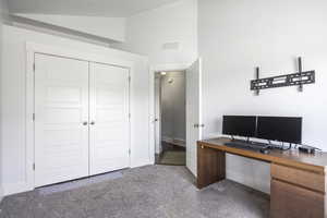 Carpeted office space with lofted ceiling and baseboards