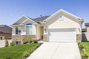 View of front of property featuring stone siding, stucco siding, an attached garage, and concrete driveway