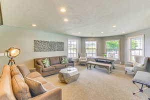 Carpeted living room featuring baseboards, recessed lighting, and a textured ceiling