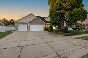 View of front facade featuring a garage, driveway, and brick siding