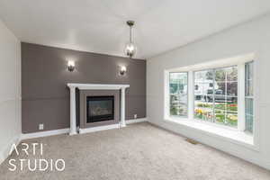 Unfurnished living room with carpet, visible vents, baseboards, and a glass covered fireplace