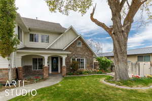 View of front of home featuring stone siding, board and batten siding, fence, and a front yard