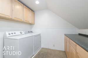 Washroom featuring wainscoting, separate washer and dryer, light colored carpet, and cabinet space
