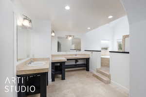 Full bathroom with a sink, two vanities, a bath, baseboards, and lofted ceiling