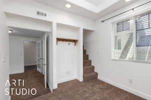 Interior space featuring stairway, carpet floors, baseboards, and visible vents