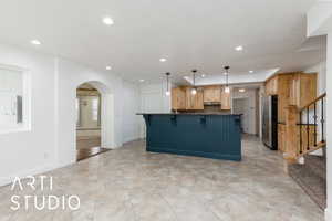 Kitchen with freestanding refrigerator, dark countertops, a kitchen breakfast bar, and recessed lighting