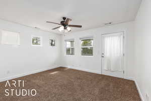 Empty room featuring dark colored carpet, plenty of natural light, and visible vents