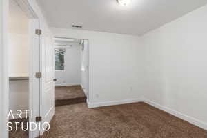 Empty room with carpet floors, baseboards, and visible vents