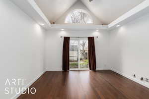 Spare room featuring lofted ceiling, baseboards, plenty of natural light, and dark wood finished floors