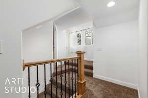 Hallway with carpet, an upstairs landing, baseboards, and lofted ceiling