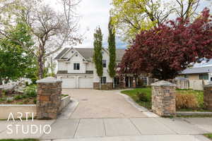 View of front of house with an attached garage, driveway, roof with shingles, and stone siding