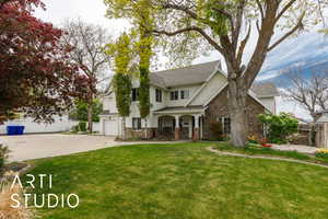 Traditional-style house featuring fence, driveway, stone siding, and a front yard