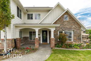 View of front of house featuring a porch, stone siding, and board and batten siding