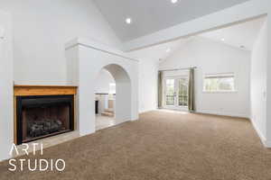 Unfurnished living room with carpet, high vaulted ceiling, recessed lighting, arched walkways, and baseboards