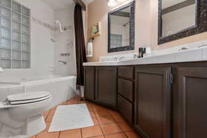 Bathroom with toilet, tiled shower / jetted bath combo, tile floors, and vanity