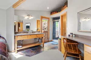 Bathroom featuring stone tile flooring, a stall shower, lofted ceiling, double vanity, and baseboards