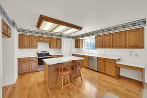 Kitchen featuring appliances with stainless steel finishes, a sink, light wood finished floors, and a breakfast bar