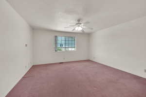 Empty room featuring light colored carpet, a ceiling fan, and baseboards