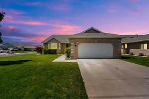 Ranch-style house featuring brick siding, a front lawn, a garage, driveway, and roof with shingles
