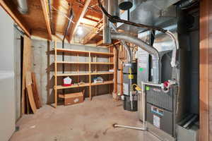 Unfinished below grade area featuring strapped water heater and heating unit