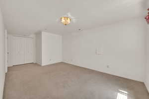 Unfurnished bedroom featuring light carpet, baseboards, and a closet
