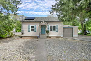 Bungalow featuring a garage, solar panels, driveway, and roof with shingles