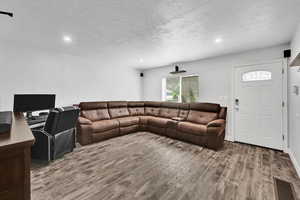 Living room featuring wood finished floors, a textured ceiling, and recessed lighting