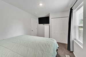 Carpeted bedroom with a closet, baseboards, and a textured ceiling