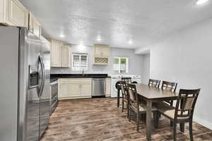 Kitchen with appliances with stainless steel finishes, washer / clothes dryer, a sink, dark wood finished floors, and a textured ceiling