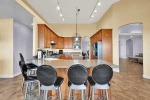 Kitchen with a sink, a peninsula, stainless steel appliances, under cabinet range hood, and arched walkways