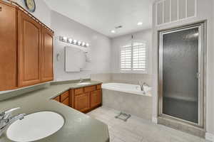 Full bath with a shower stall, a garden tub, vanity, and visible vents