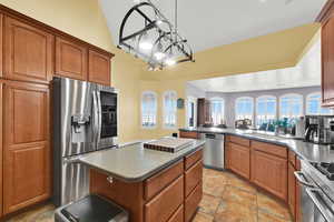 Kitchen featuring a sink, a peninsula, brown cabinets, and appliances with stainless steel finishes