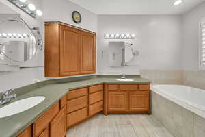 Bathroom with recessed lighting, a garden tub, double vanity, and a sink