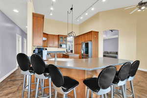 Kitchen featuring a breakfast bar, a center island, a ceiling fan, baseboards, and appliances with stainless steel finishes