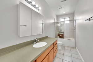 Full bath with toilet, visible vents, shower / bath combination with glass door, tile patterned flooring, and vanity