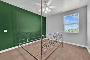 Carpeted bedroom featuring baseboards, visible vents, and a ceiling fan