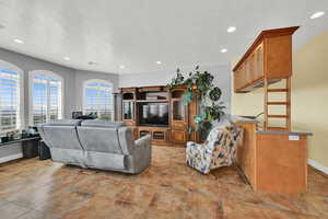 Living room with baseboards, stone finish flooring, recessed lighting, and a textured ceiling