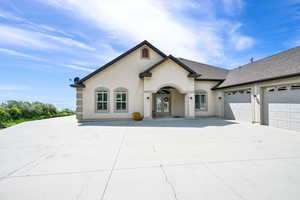 View of front of home with an attached garage, french doors, stucco siding, roof with shingles, and driveway