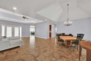 Dining space featuring arched walkways, baseboards, recessed lighting, and ceiling fan with notable chandelier