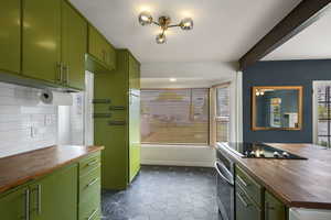 Kitchen featuring butcher block countertops, stainless steel oven, black electric stovetop, and green cabinetry