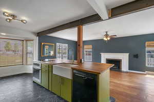 Kitchen with black dishwasher, wooden counters, green cabinets, stainless steel oven, and a sink