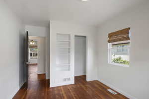 Unfurnished bedroom with baseboards, dark wood-style flooring, and a closet