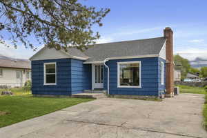 View of front of home featuring a chimney and a shingled roof
