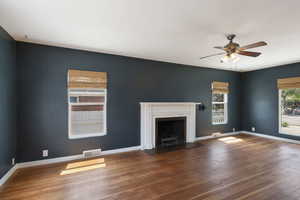 Unfurnished living room featuring wood finished floors, ceiling fan, a fireplace with flush hearth, and baseboards
