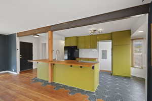 Kitchen with freestanding refrigerator, green cabinets, baseboards, butcher block counters, and tasteful backsplash