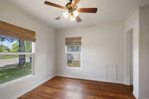 Empty room featuring wood finished floors, baseboards, and ceiling fan