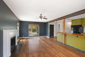 Unfurnished living room with a ceiling fan, hardwood / wood-style flooring, a fireplace with flush hearth, and baseboards