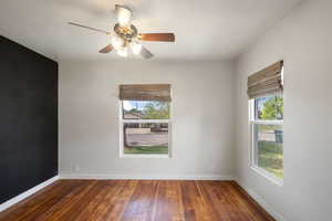 Empty room featuring hardwood / wood-style floors, baseboards, and a ceiling fan